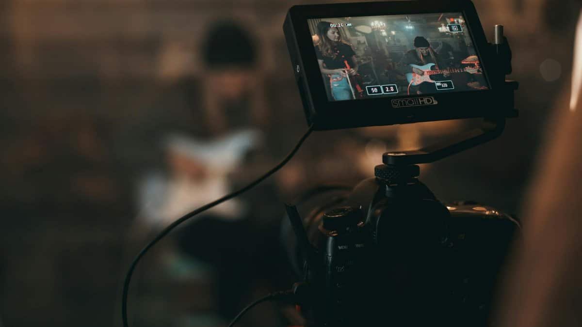A cinematic close-up of filming a rock band performance with focus on camera screen.