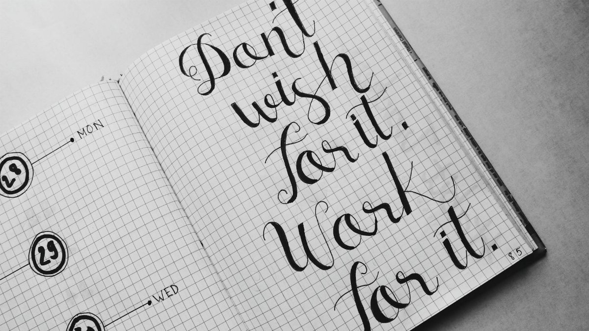 Close-up of motivational calligraphy on grid paper, inspiring message for productivity.
