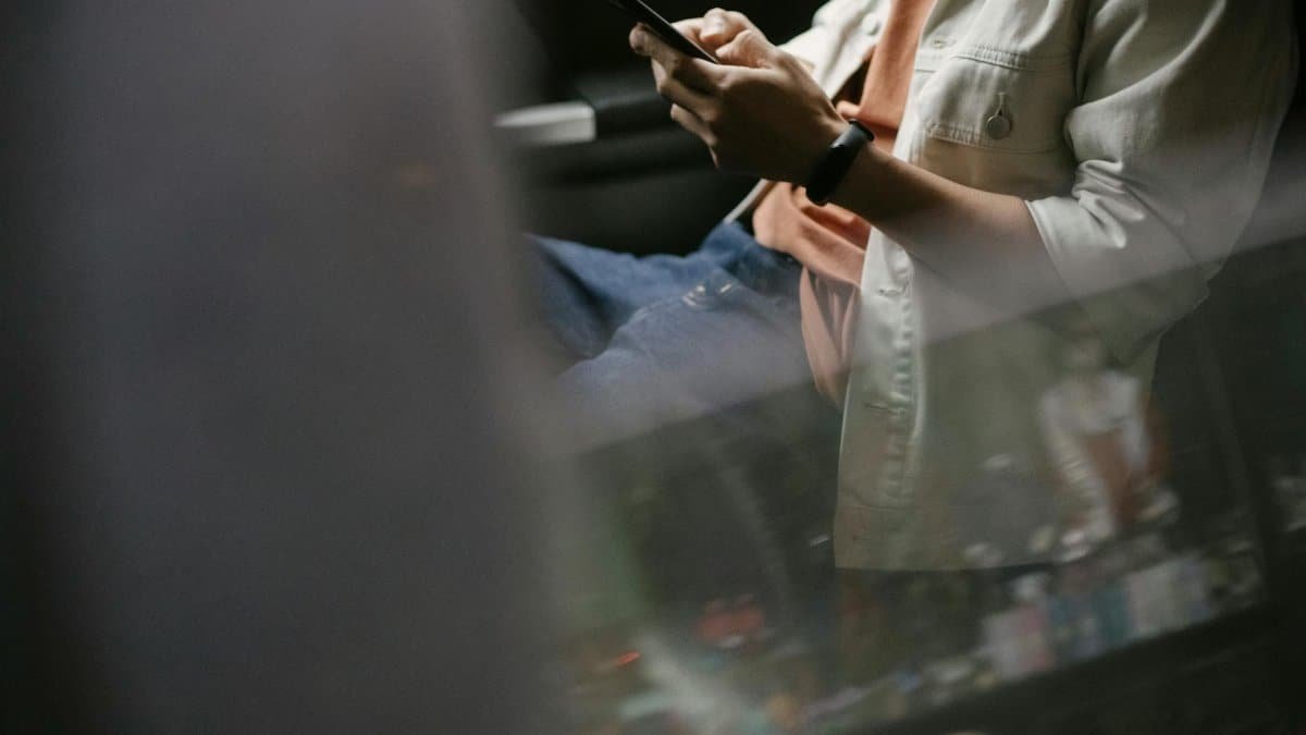 Casual man texting on smartphone while traveling as a passenger in a car.