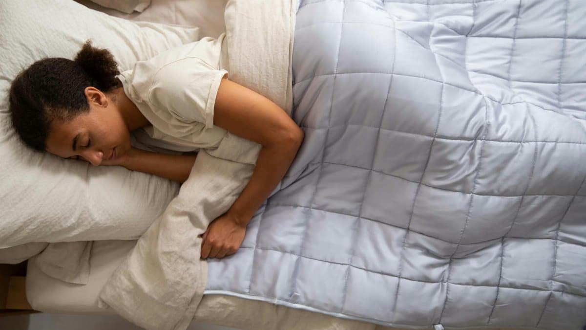 Young woman peacefully resting with a weighted blanket, enjoying relaxation and comfort.