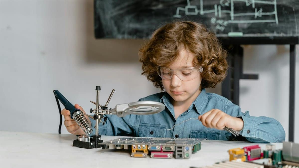 Child working on electronics with a soldering tool and circuit board, showcasing STEM learning.