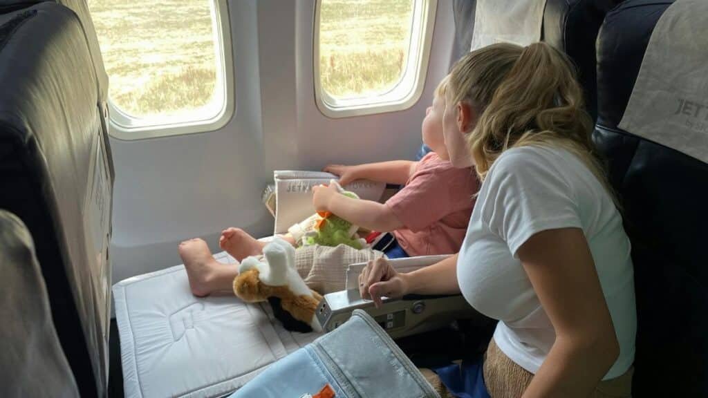 Mother and child sitting inside airplane, enjoying scenic view through windows during flight travel.