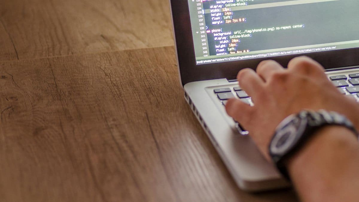 Close-up of a person coding on a laptop, showcasing web development and programming concepts.