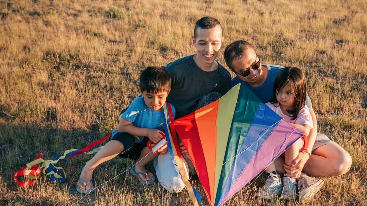 Happy family with children flying a colorful kite in a sunny field, sharing joyful moments together.