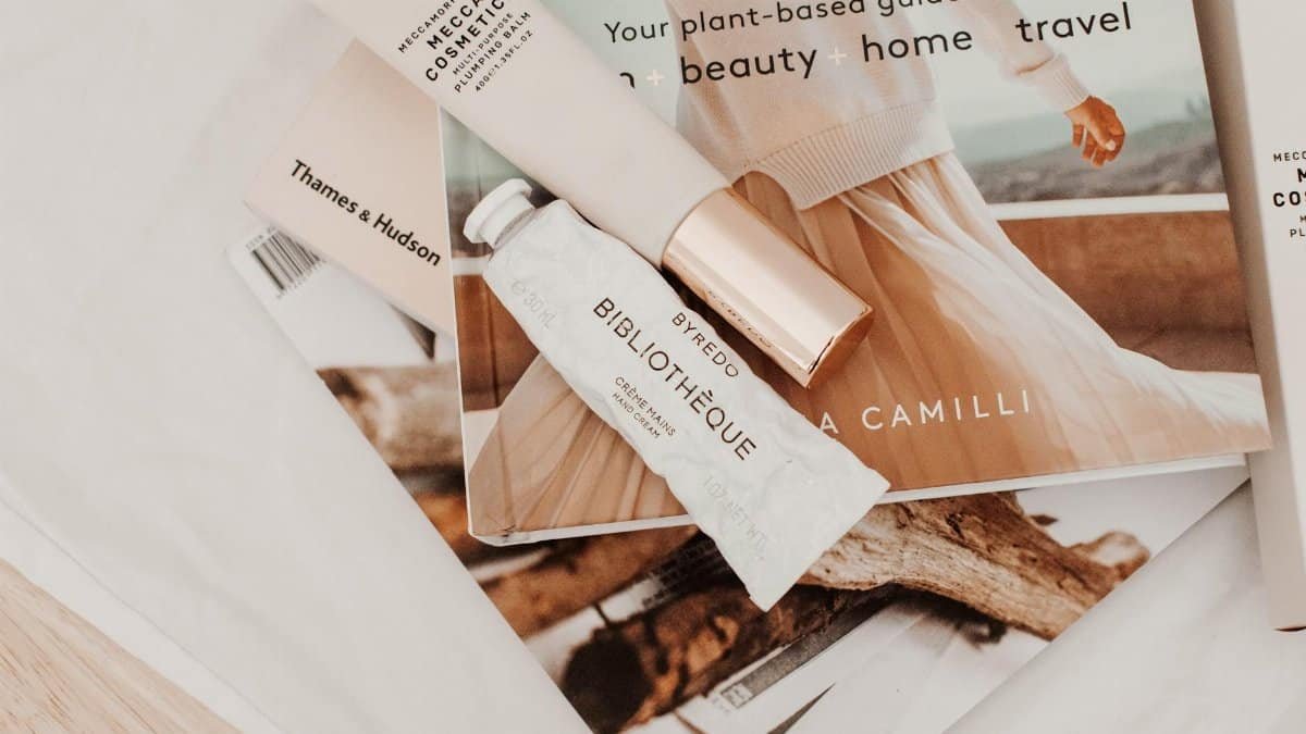 Minimalist flat lay with cosmetics and magazines showcasing modern lifestyle.