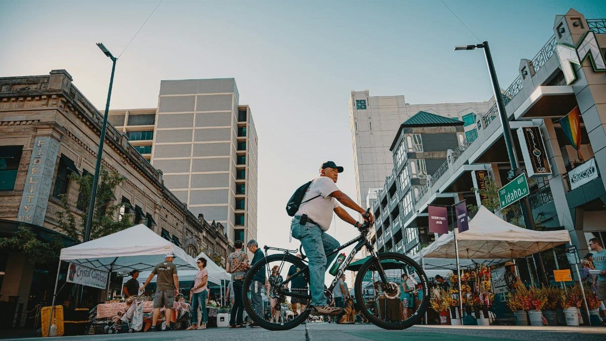 Cyclist navigating a bustling outdoor market in a vibrant urban city setting.