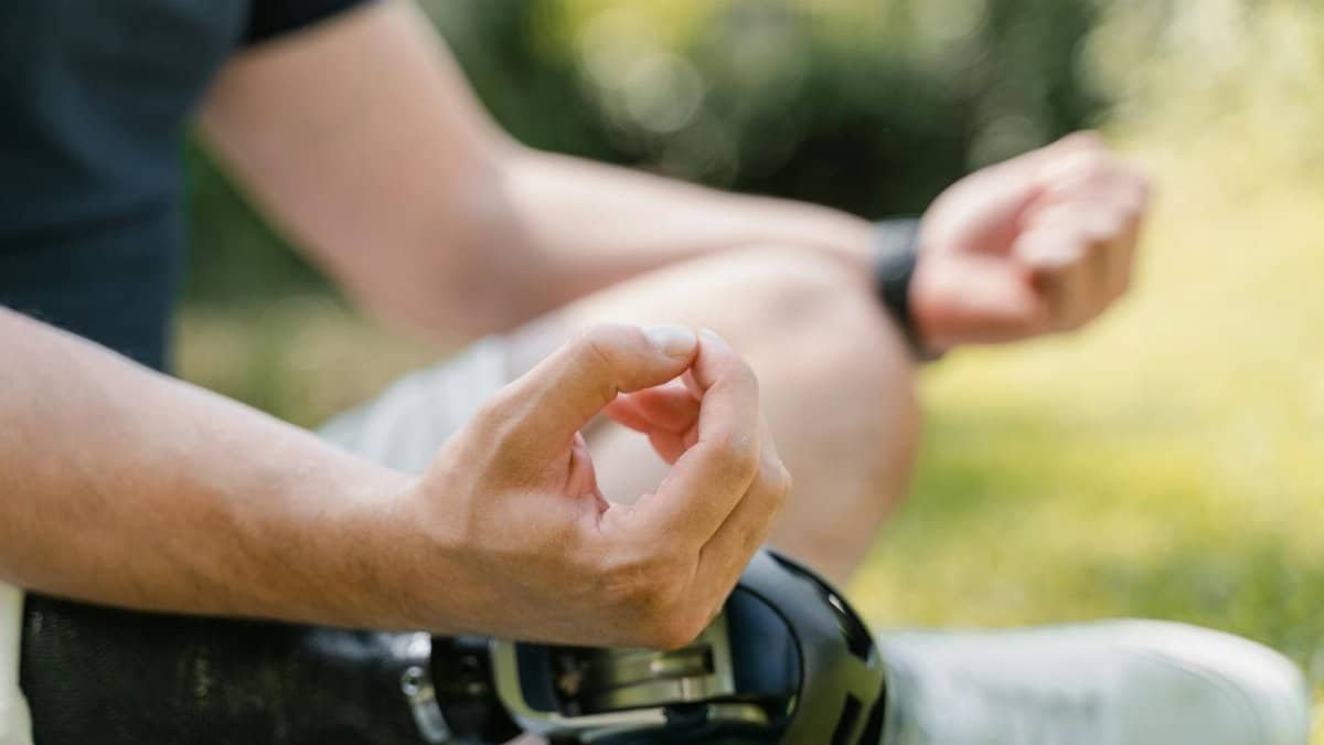 Close-up of a person meditating outdoors, showcasing a prosthetic leg, emphasizing mindfulness and technology integration.