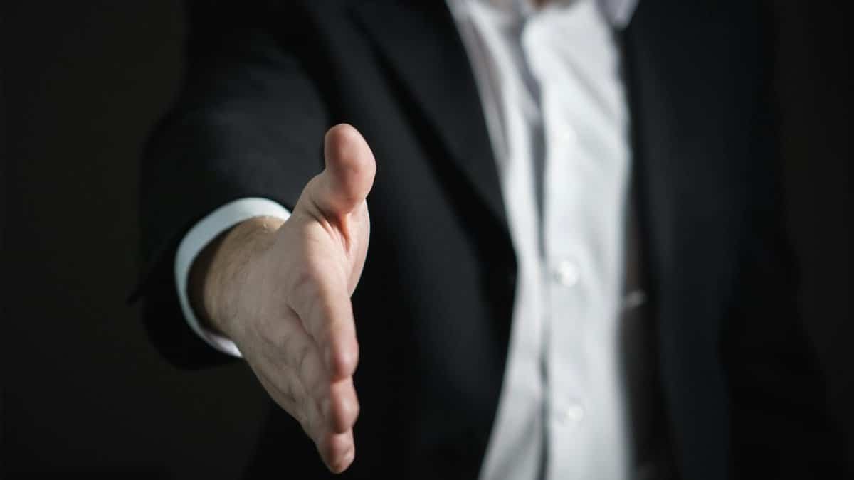 Close-up of a businessman extending hand for a handshake, symbolizing agreement and partnership.