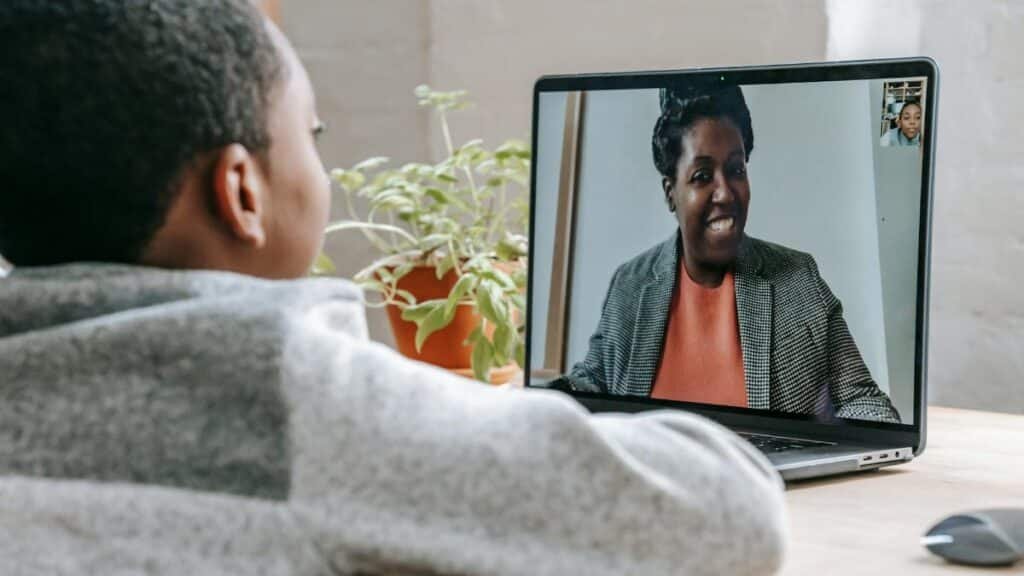 A young boy participates in online learning through a video call on his laptop.