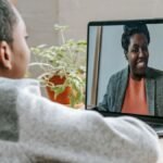 A young boy participates in online learning through a video call on his laptop.