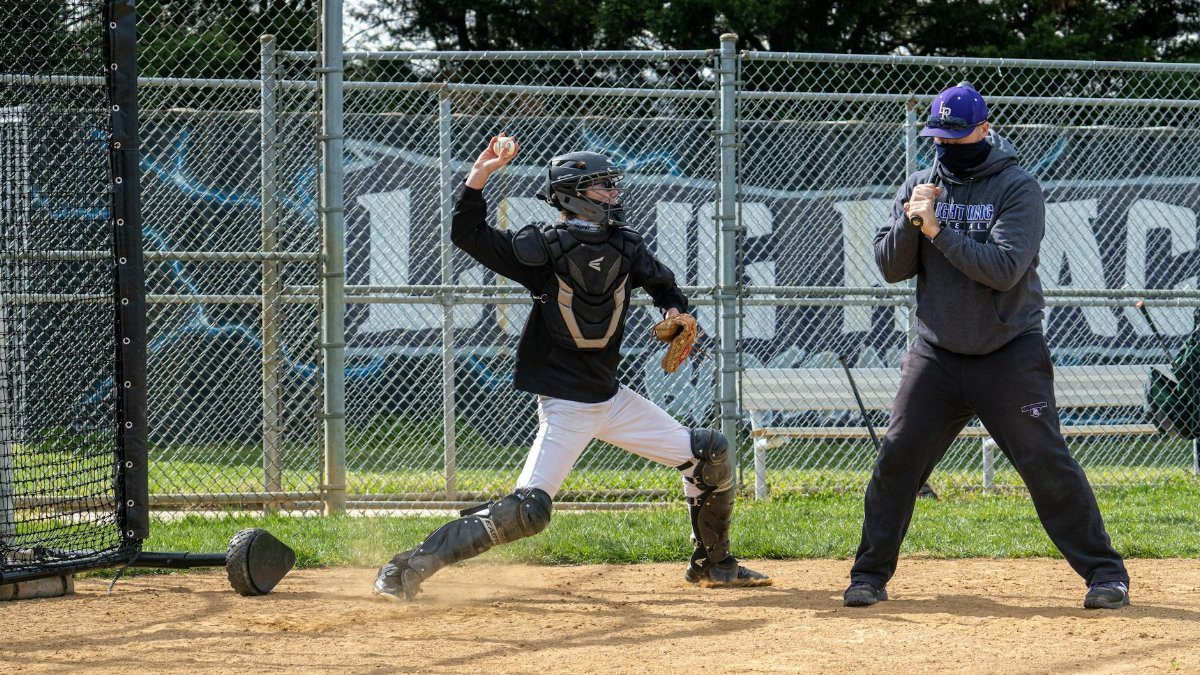 Catcher in baseball gear practicing on an outdoor field in Columbia, MD.
