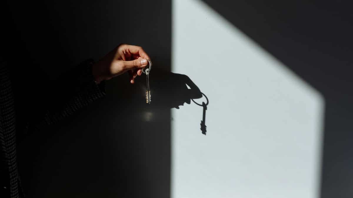 Minimalist photo of a hand holding a key casting a shadow, signifying property ownership