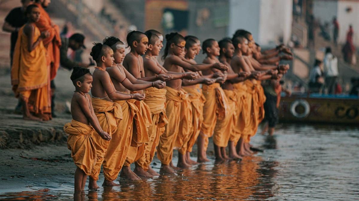 Group of young monks in saffron robes performing a ritual on the Ganges River in Varanasi.