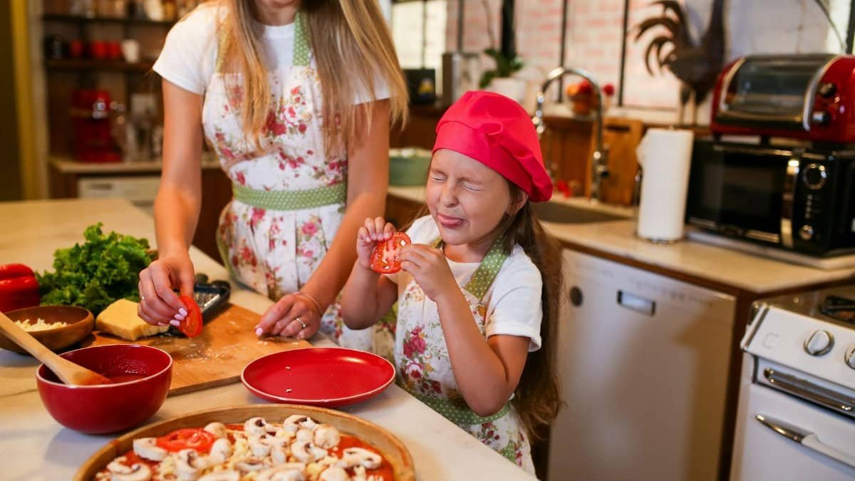 Happy mother and daughter making pizza together in a home kitchen, sharing quality family time.