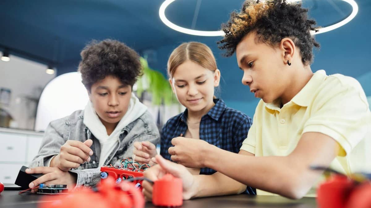 Diverse teenagers collaboratively working on a robotics project in a workshop.