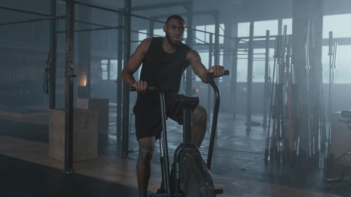 Focused man in gym working out on elliptical machine, promoting fitness and lifestyle.