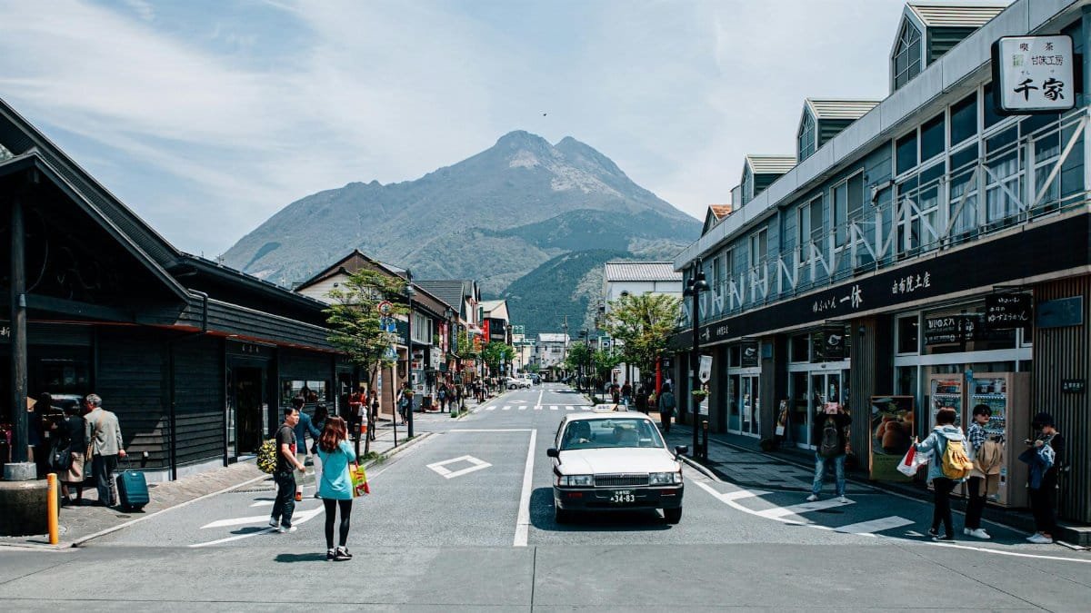 Dynamic town street scene with shopping and mountain backdrop, showcasing urban life.