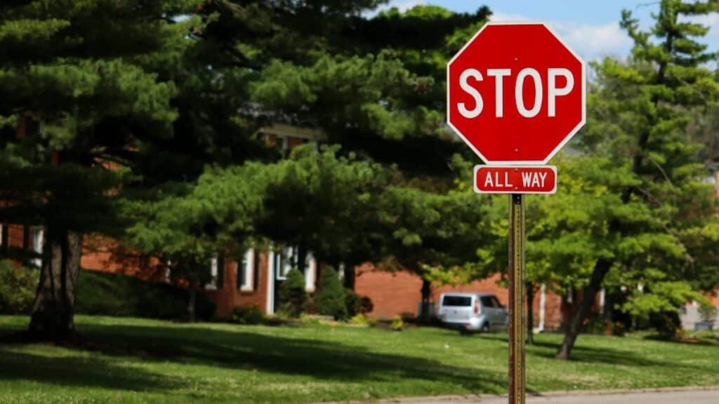 A stop sign on an Indianapolis street with suburban houses and lush green trees.