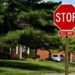 A stop sign on an Indianapolis street with suburban houses and lush green trees.