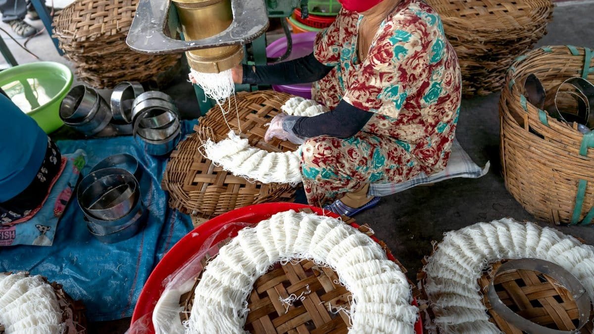 Woman making traditional noodles outdoors, showcasing craftsmanship and cultural heritage.