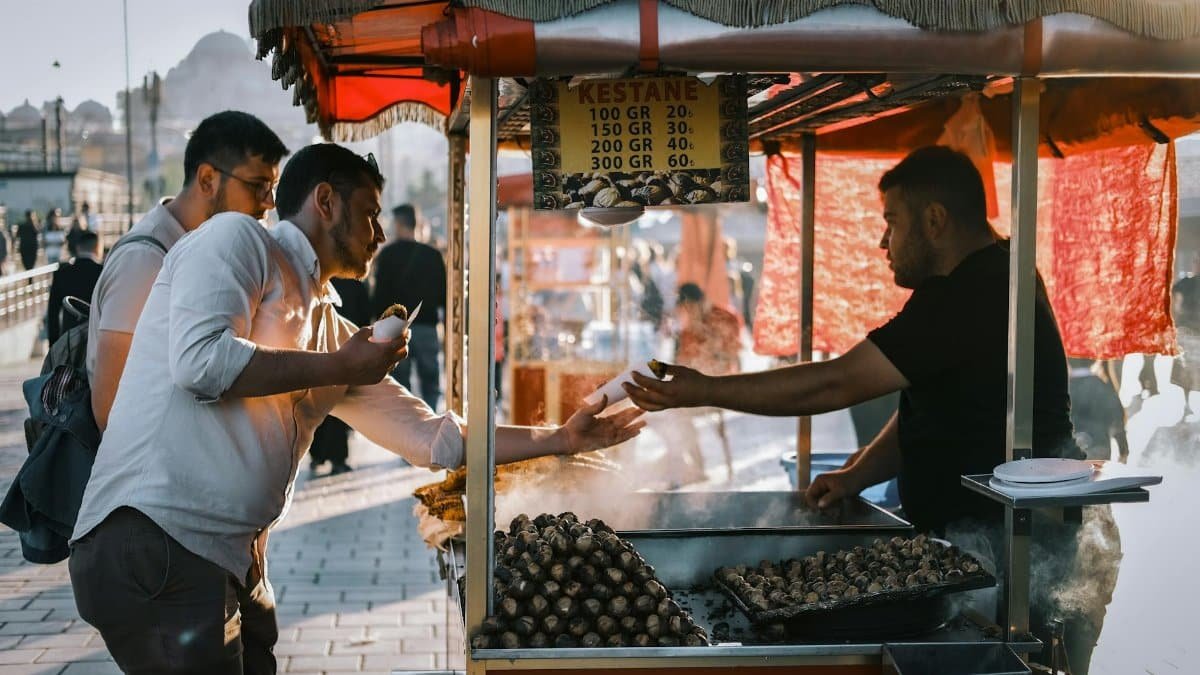 A bustling street market scene with people buying roasted chestnuts in İstanbul.
