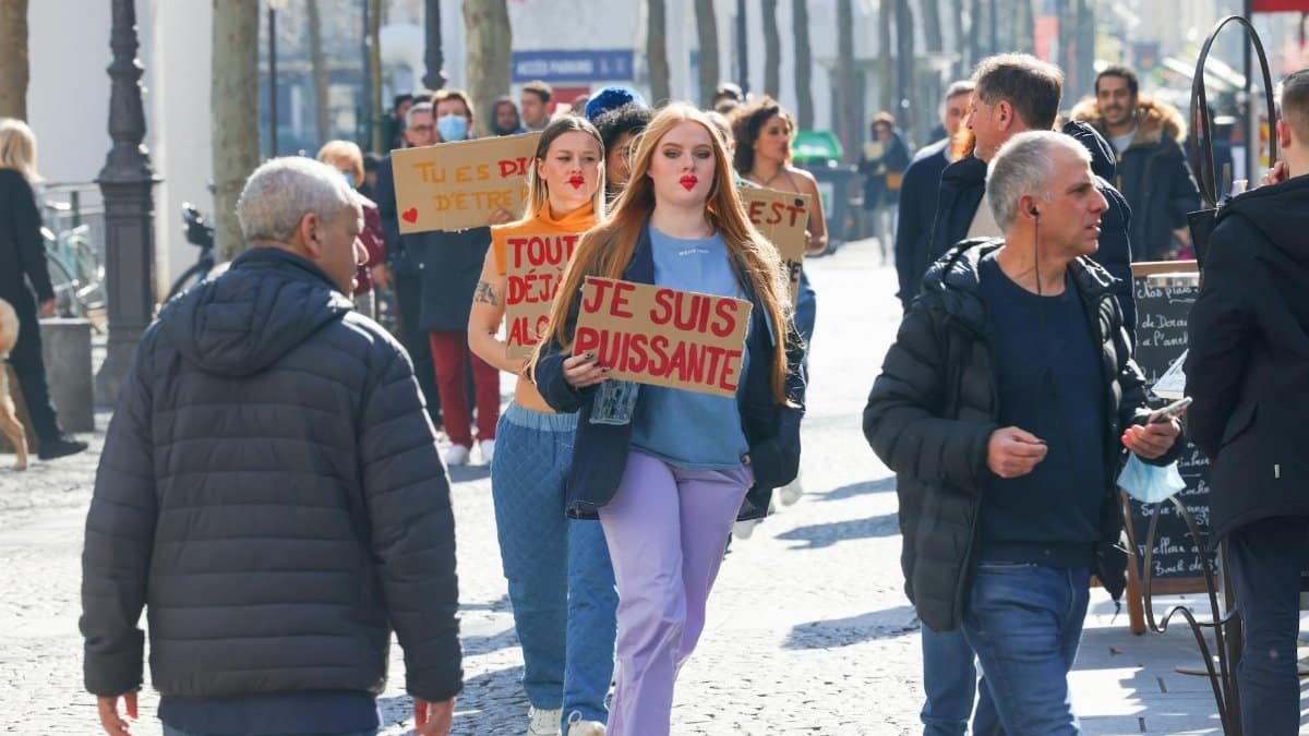 Women protesting in a city street holding signs in French, advocating for empowerment.
