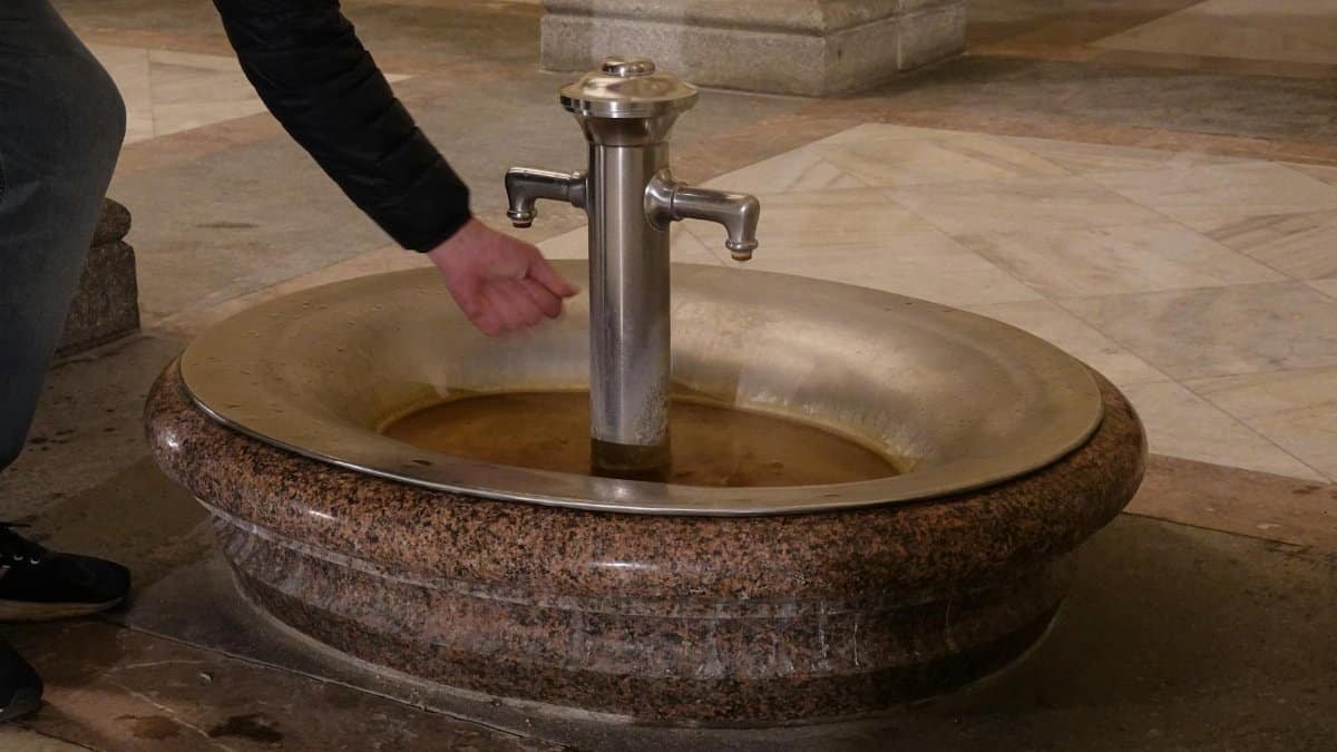 A person using a historical fountain in Karlovy Vary, Czechia.