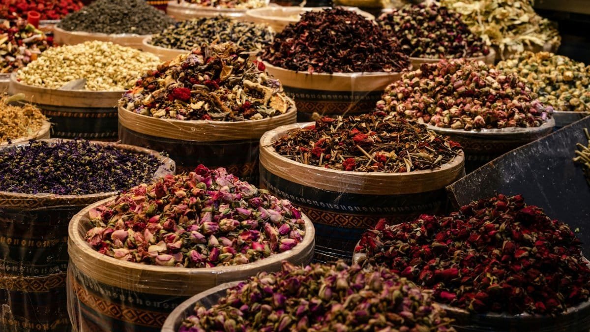 A colorful display of dried spices and herbs in barrels at a bustling market.