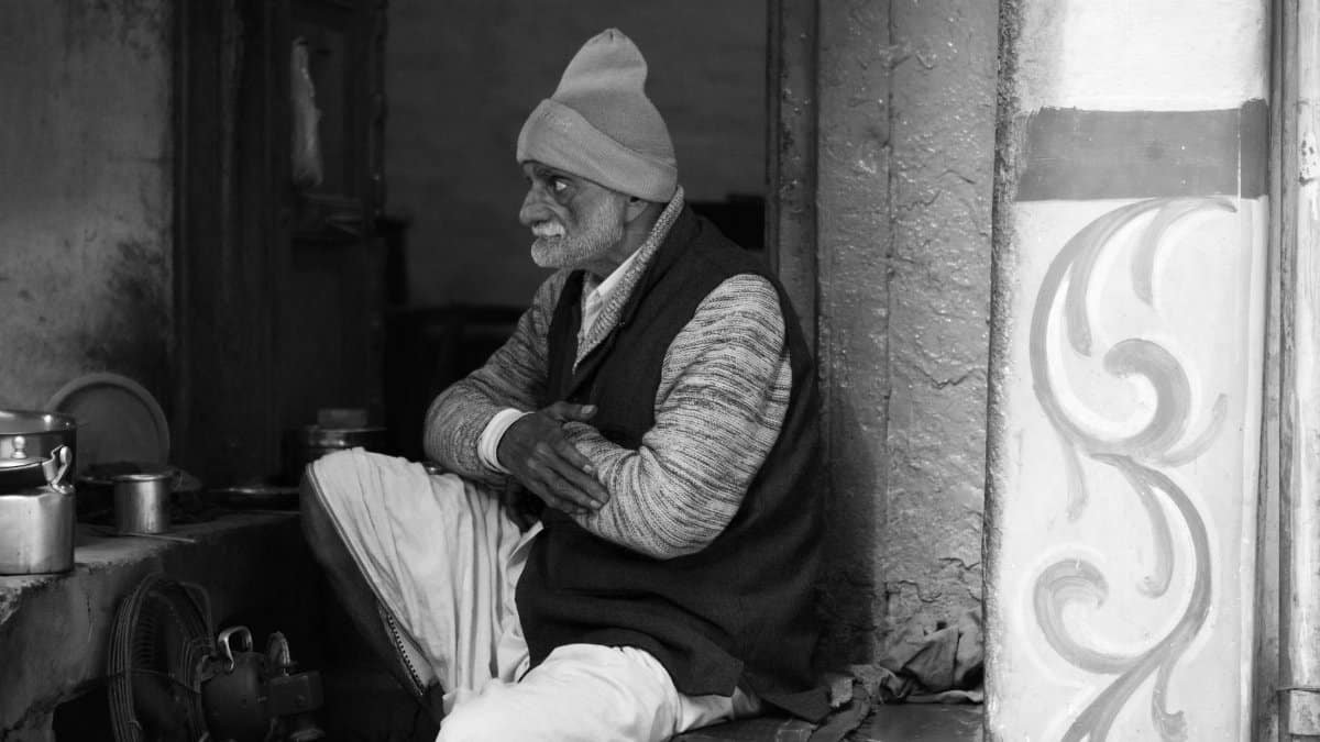 Black and white photo of an elderly man sitting in Varanasi, India, in thoughtful contemplation.