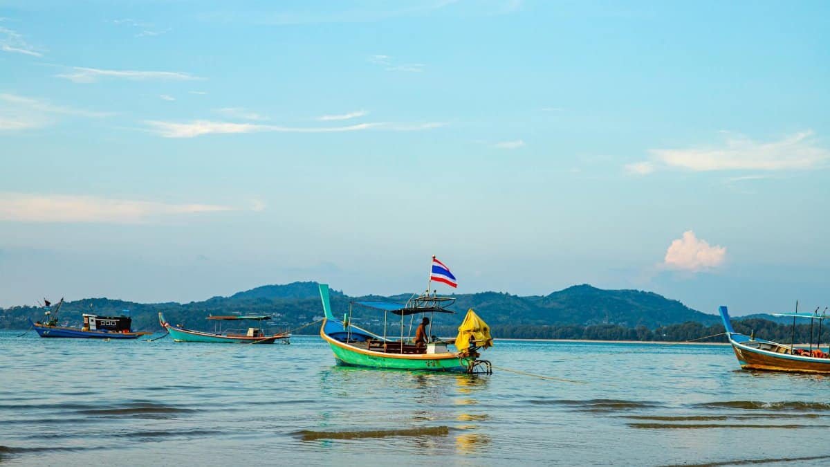 Traditional long-tail boats anchored on a tranquil sea in Phuket, Thailand during day time.
