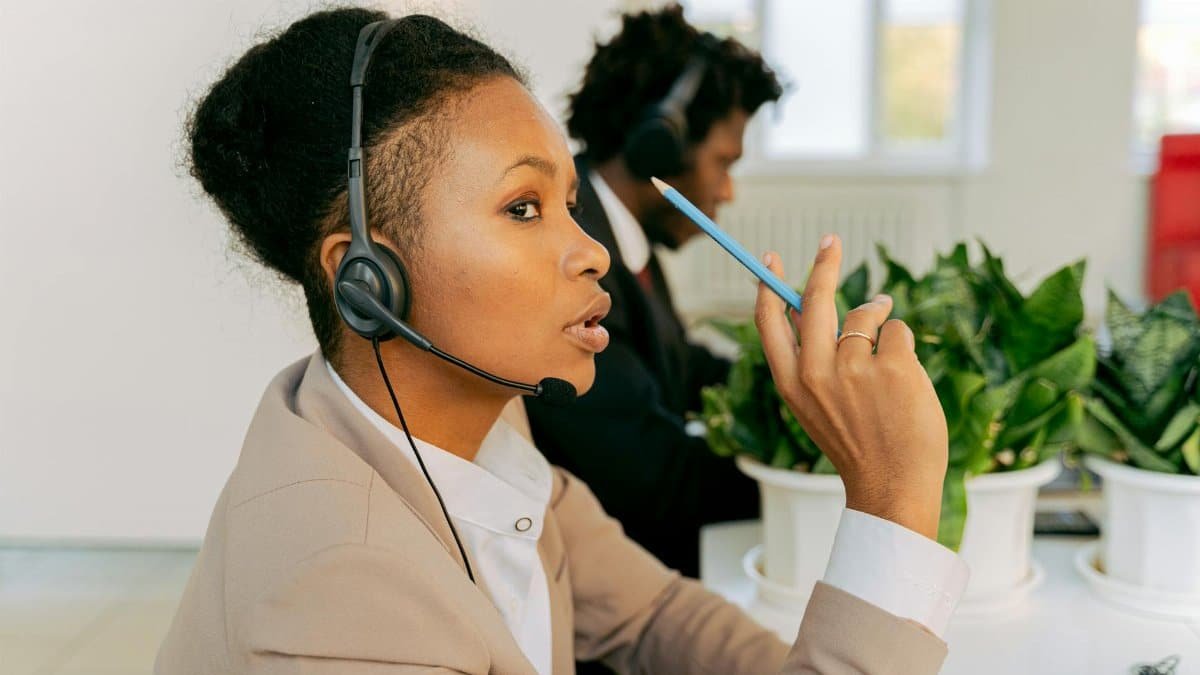 Two call center agents focused on customer service, wearing headsets in an office.