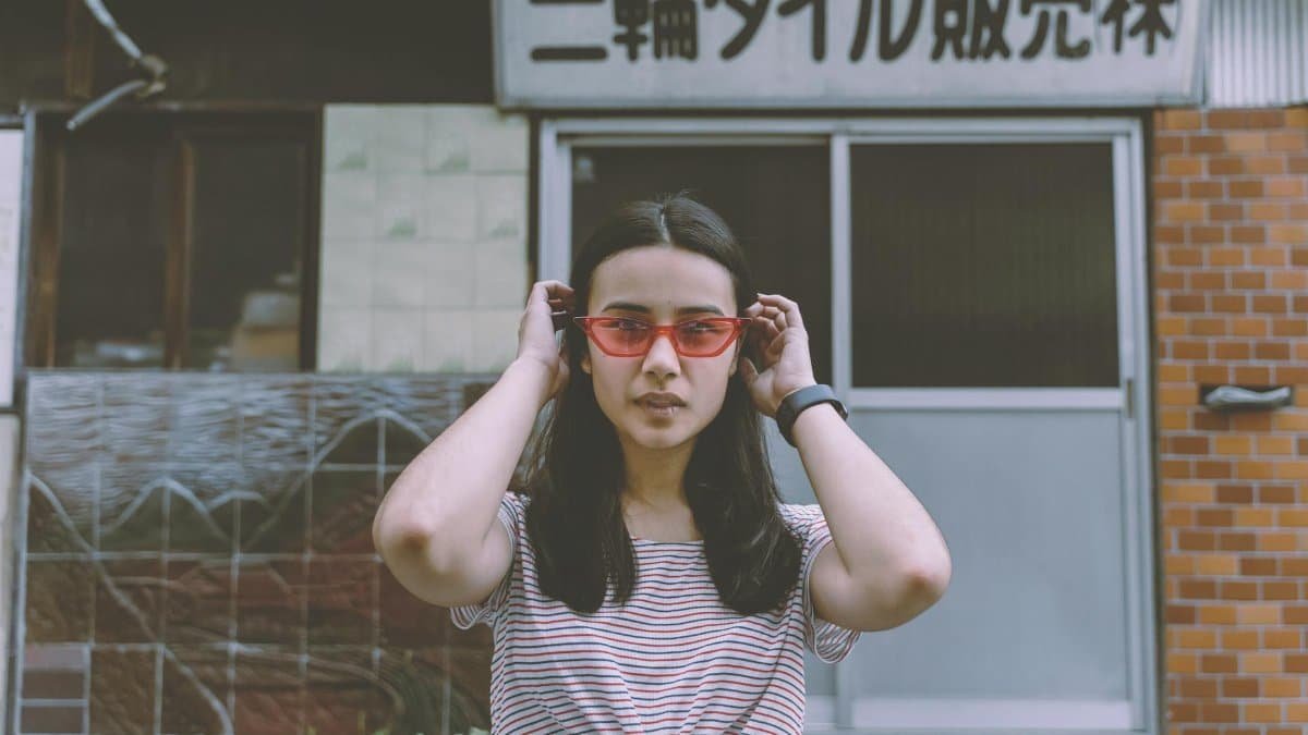 Stylish young woman in eyewear poses confidently on urban Tokyo street.