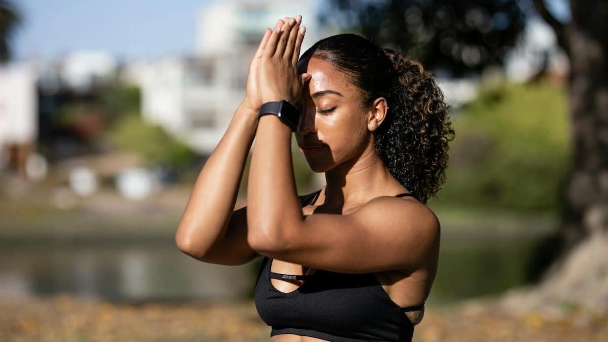 African American woman meditating outdoors, promoting relaxation and wellness.