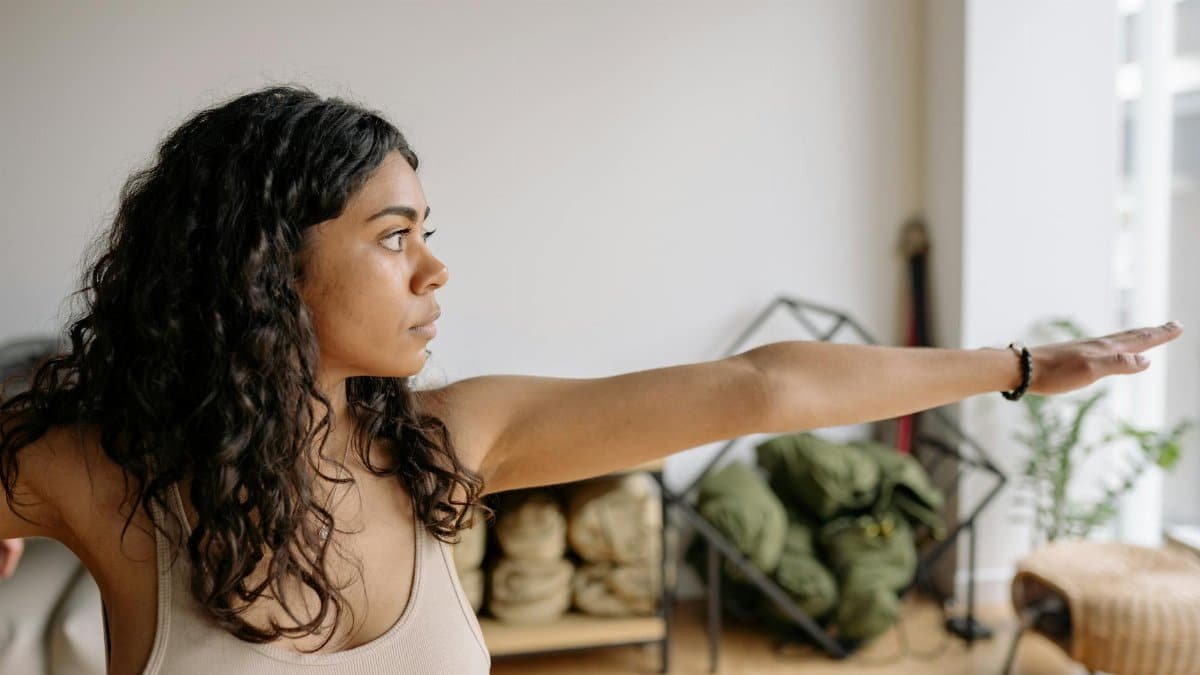 Side view of a young woman stretching and practicing yoga indoors for a healthy lifestyle.