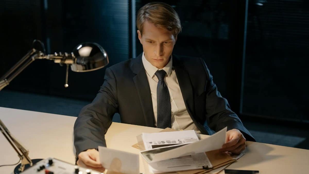 Focused investigator reviewing evidence in a dimly lit office setting.