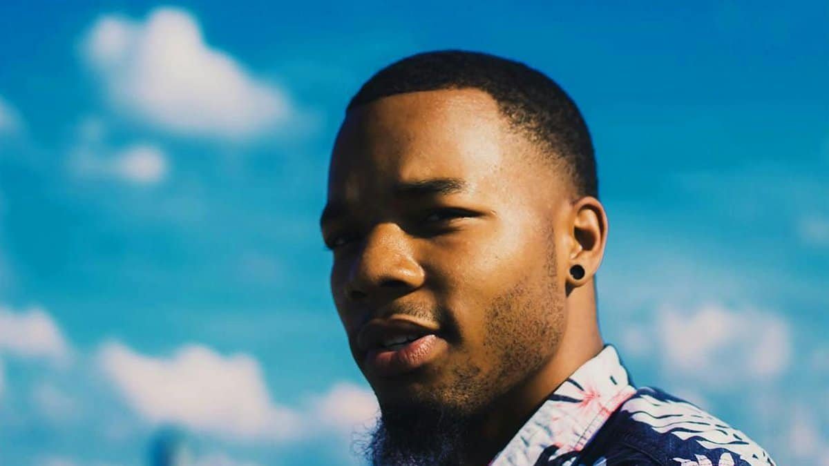 Close-up of a young African American man with a floral shirt against a blue sky in Atlanta.