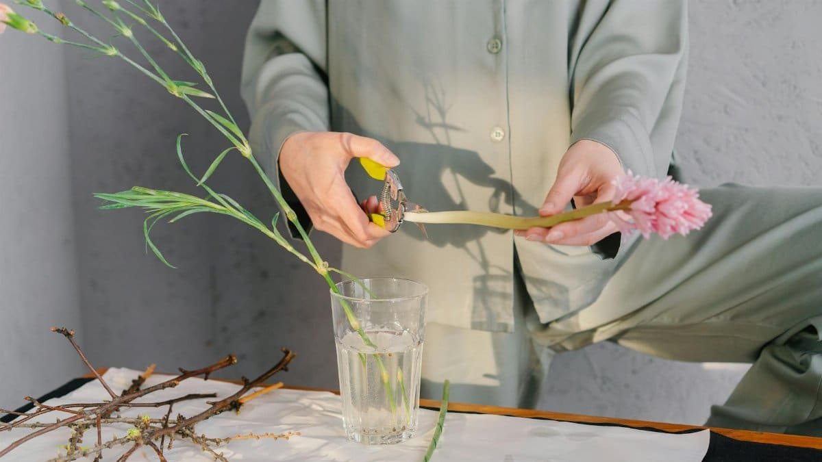 A person trims flowers for a floral arrangement, emphasizing creativity and mindfulness.
