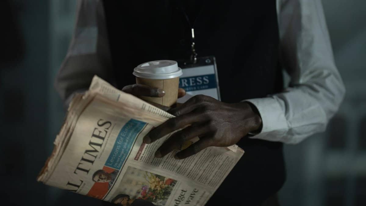 Close-up of a journalist holding a newspaper and coffee cup, conveying press and media concept.