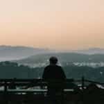 A man sits on a bench overlooking San Francisco at sunset, capturing a serene and contemplative moment.