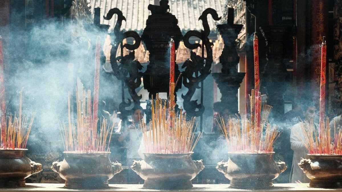 Incense burning during a ceremonial worship at a Vietnamese temple, vibrant smoke fills the air.
