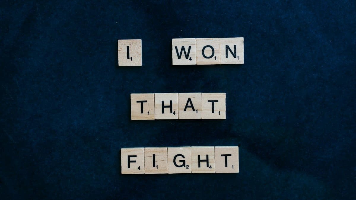 Wooden Scrabble tiles on dark background spelling 'I won that fight.'