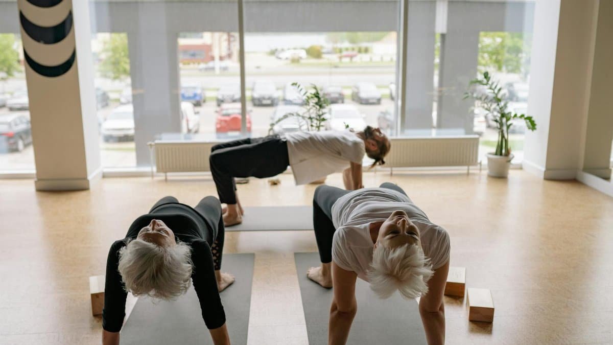 Senior adults in a yoga class practicing reverse table pose in a serene studio.