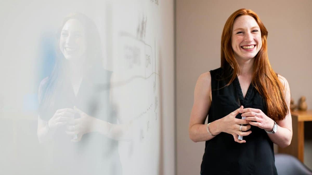 Confident businesswoman smiling during a corporate presentation in a modern office setting.