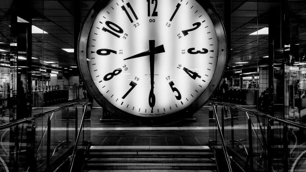 Monochrome image of a large clock at a train station, conveying the passage of time.