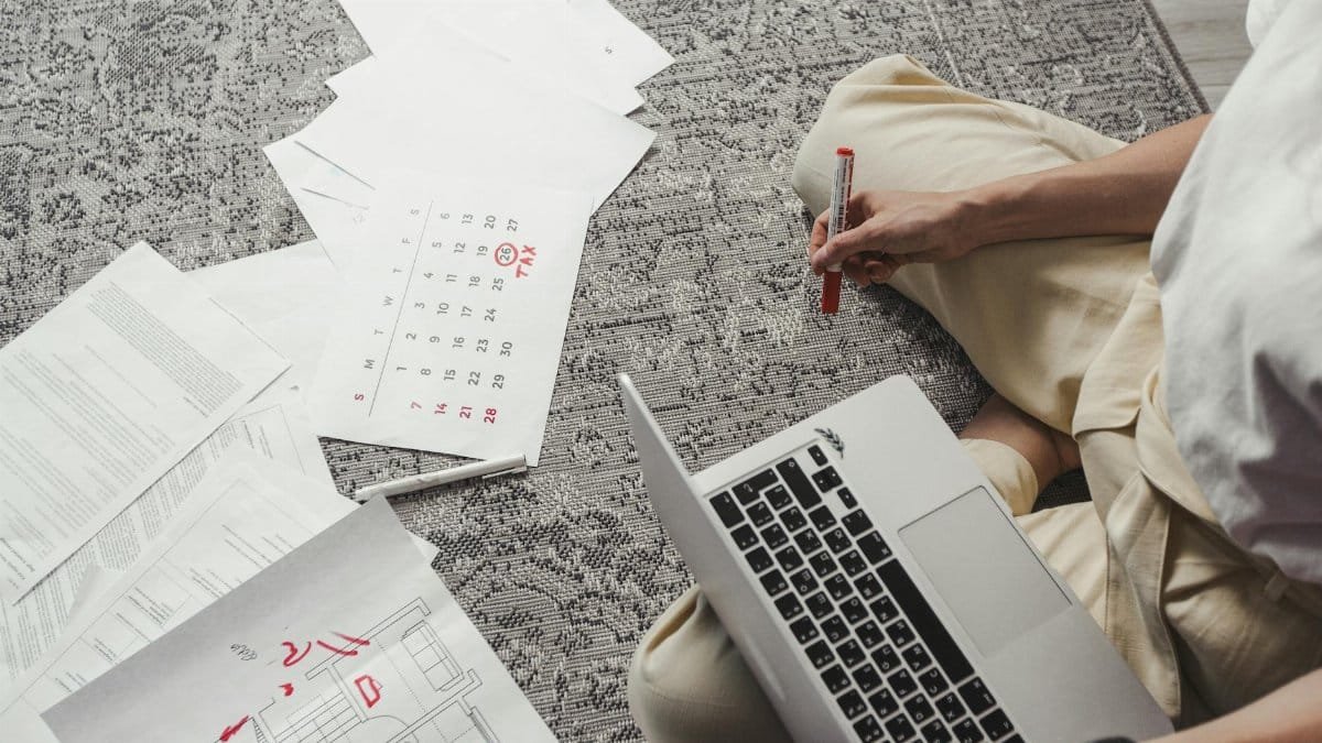 Young man working on plans with laptop and calendar, organizing tasks and schedules.
