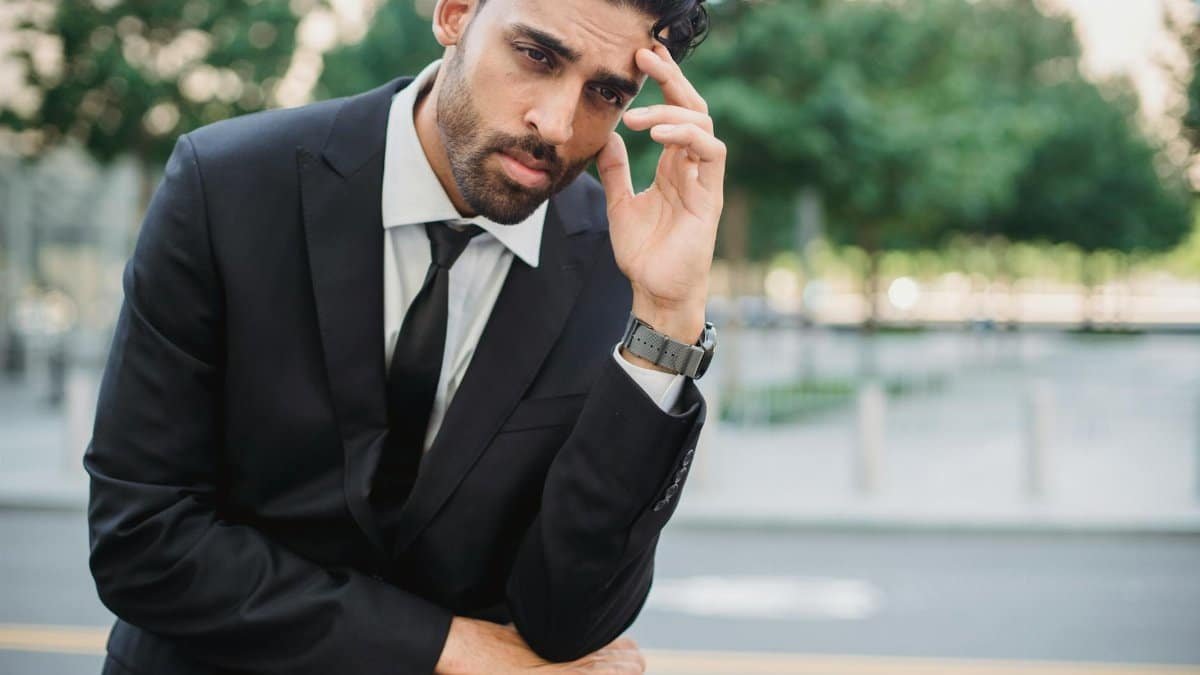 A thoughtful businessman in a suit outdoors, contemplating decisions.