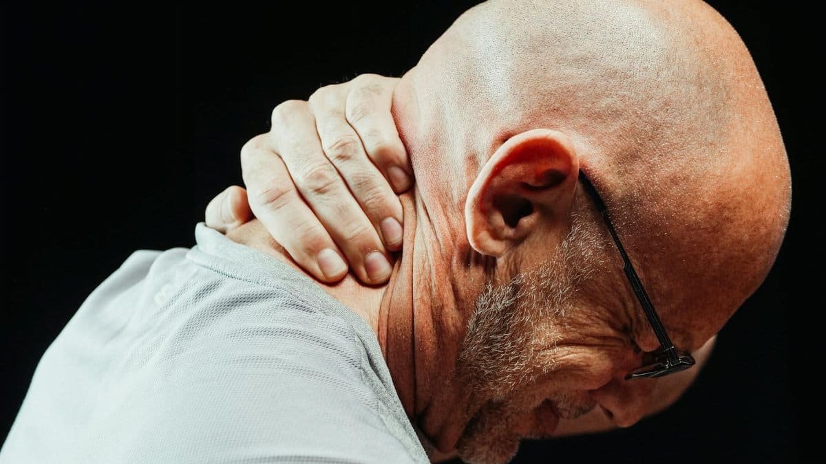 Side view of senior man holding neck with visible discomfort, highlighting neck pain relief.
