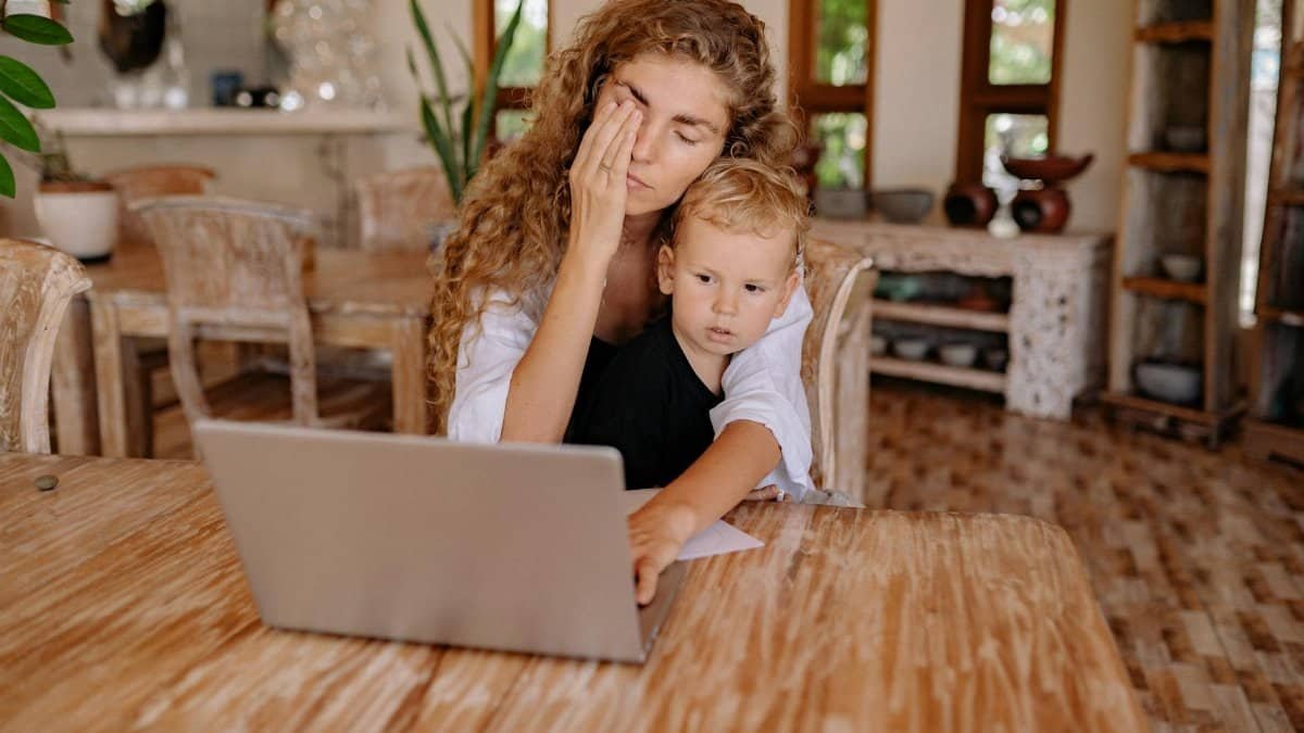 Woman multitasking while working from home with child. Relaxed ambiance.