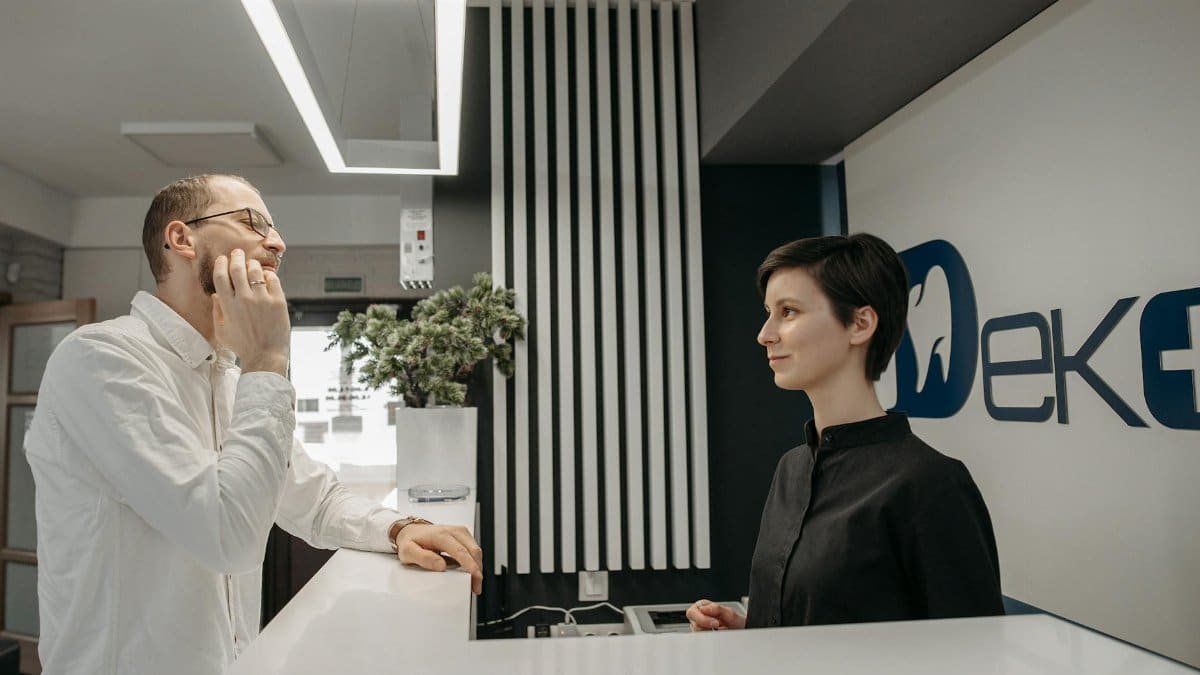 Patient discussing dental issues at a modern clinic reception with a receptionist.