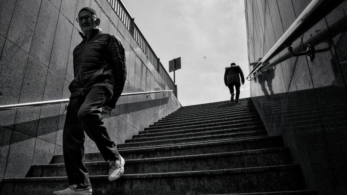 Black and white image of two men on city steps, depicting urban life.